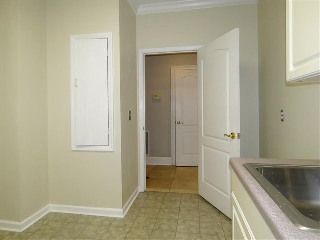 laundry area with ornamental molding, light tile patterned flooring, and sink