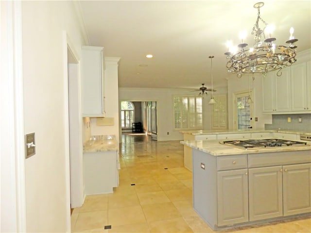 kitchen with stainless steel gas cooktop, hanging light fixtures, plenty of natural light, and white cabinets