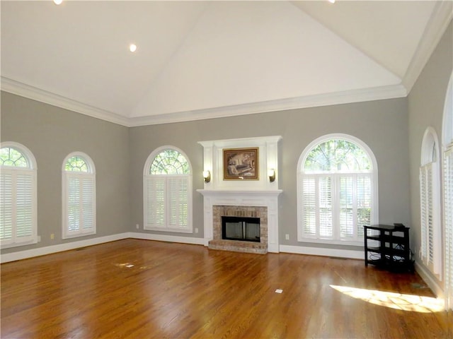 unfurnished living room featuring a wealth of natural light, a fireplace, hardwood / wood-style flooring, and high vaulted ceiling