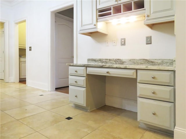 kitchen with built in desk, light stone counters, and light tile patterned floors