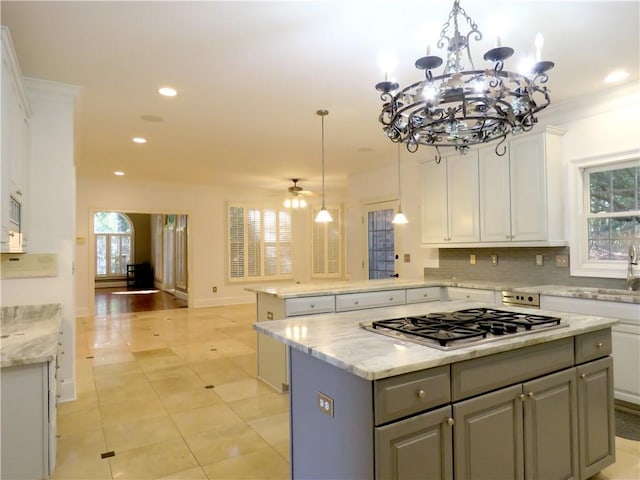 kitchen featuring stainless steel gas cooktop, white cabinets, a center island, and hanging light fixtures