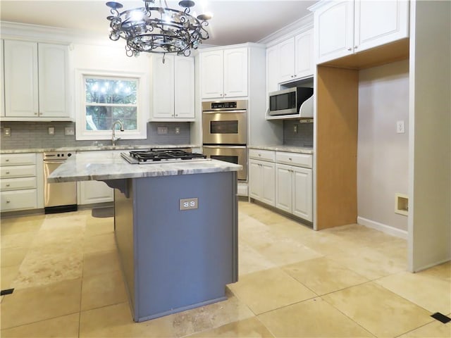 kitchen featuring decorative backsplash, white cabinets, stainless steel appliances, decorative light fixtures, and a center island