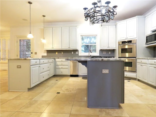 kitchen featuring decorative backsplash, a center island, decorative light fixtures, white cabinetry, and appliances with stainless steel finishes