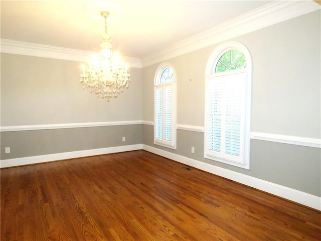 empty room with ornamental molding, a notable chandelier, and hardwood / wood-style floors