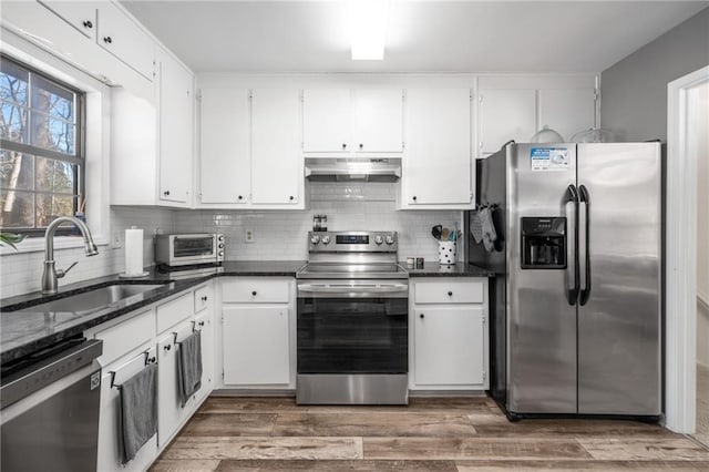 kitchen featuring sink, white cabinets, stainless steel appliances, and dark stone countertops