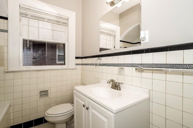 bathroom with toilet, vanity, and tile walls