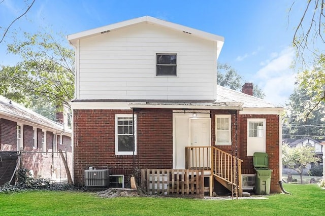 rear view of property with brick siding, a lawn, and cooling unit