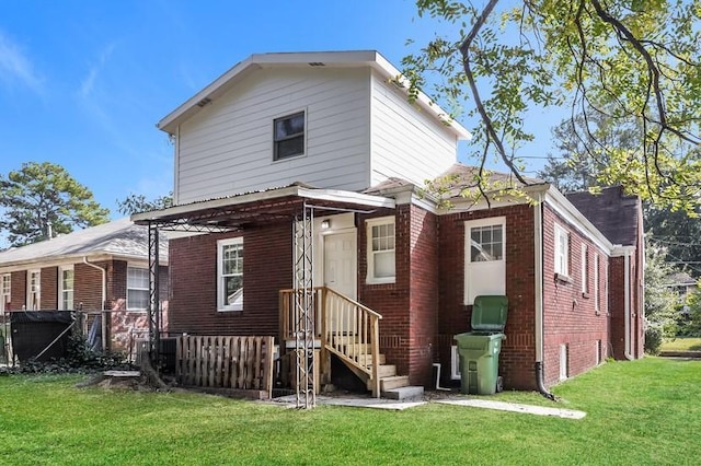 rear view of property with brick siding and a yard