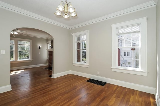 unfurnished dining area with a healthy amount of sunlight, dark wood-style floors, visible vents, and arched walkways