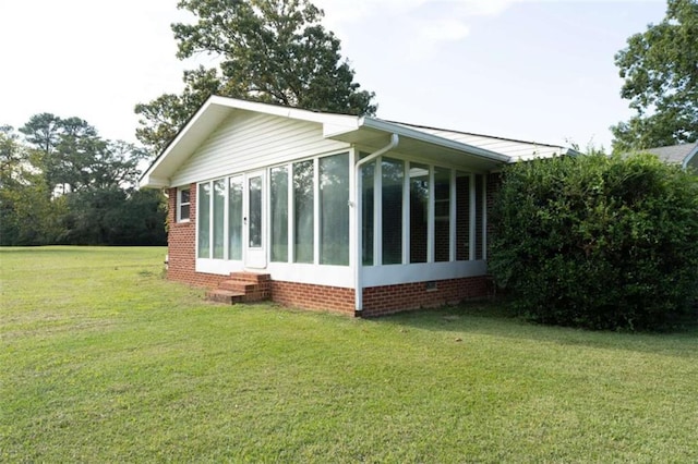 view of home's exterior with a sunroom and a lawn