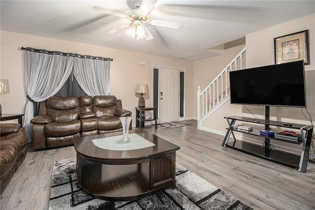 living room featuring a textured ceiling, light hardwood / wood-style flooring, and ceiling fan