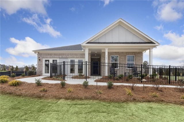 back of property with brick siding, board and batten siding, fence, and a lawn