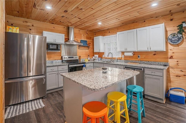 kitchen featuring range hood, a center island, gray cabinetry, appliances with stainless steel finishes, and dark wood finished floors
