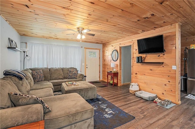 living room featuring wooden ceiling, wooden walls, a ceiling fan, baseboards, and wood finished floors