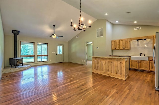 kitchen featuring dark hardwood / wood-style flooring, tasteful backsplash, sink, pendant lighting, and a wood stove