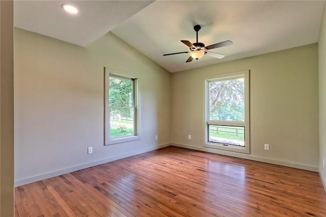 empty room featuring hardwood / wood-style flooring, ceiling fan, a healthy amount of sunlight, and vaulted ceiling