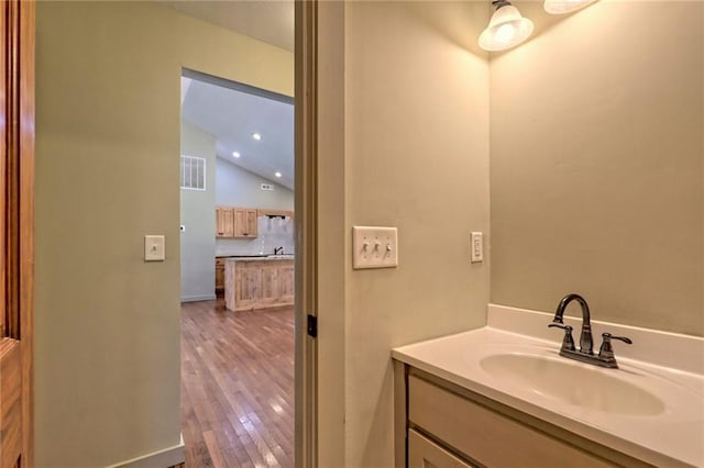 bathroom with hardwood / wood-style flooring, vanity, and lofted ceiling