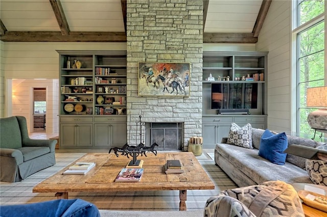 living room featuring beam ceiling, high vaulted ceiling, a stone fireplace, and wooden walls