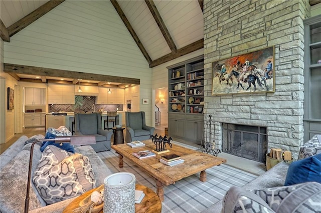 living room with beamed ceiling, built in shelves, a stone fireplace, and high vaulted ceiling