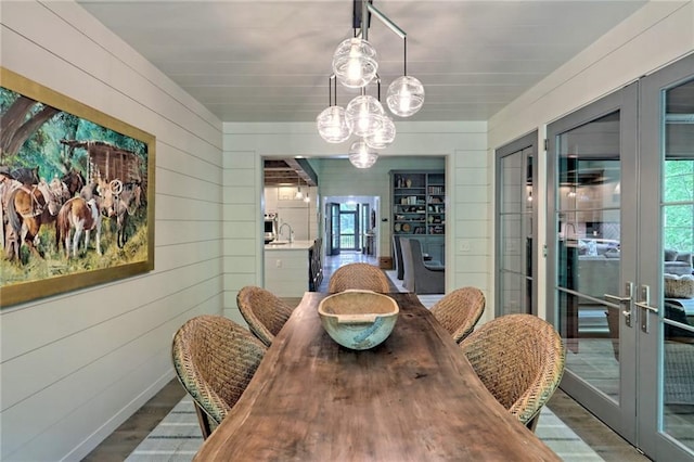 dining space with hardwood / wood-style floors, french doors, sink, and wood walls