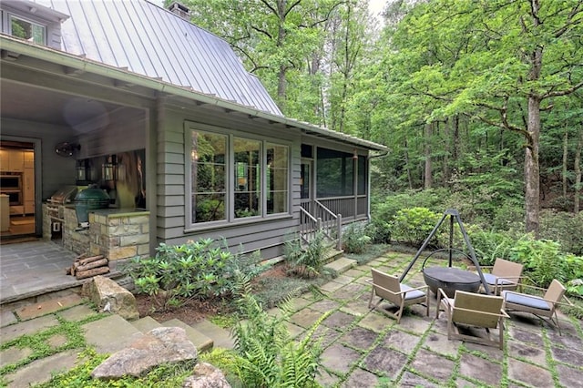 view of patio / terrace featuring a sunroom and an outdoor kitchen