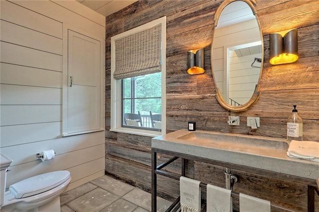 bathroom featuring tile patterned flooring, toilet, and wooden walls