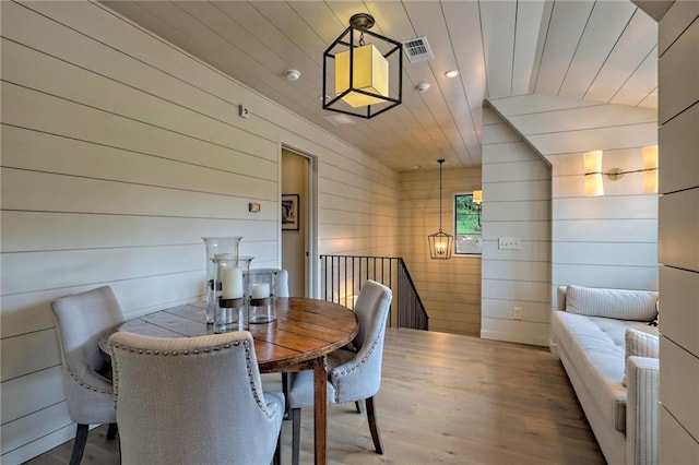 dining space with vaulted ceiling, wooden ceiling, and wood walls