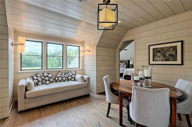 dining space with wood walls, wooden ceiling, lofted ceiling, and light wood-type flooring