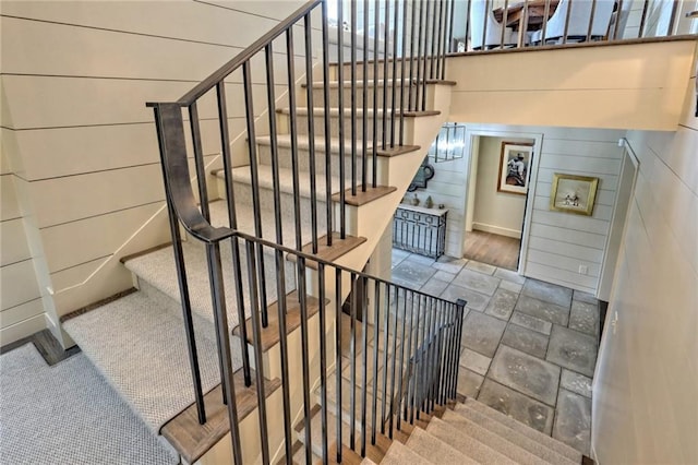 stairway featuring wood walls