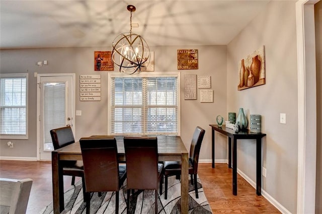 dining space featuring a chandelier, baseboards, and wood finished floors