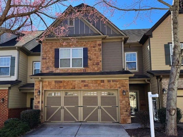 townhome / multi-family property with a garage, stone siding, board and batten siding, and driveway