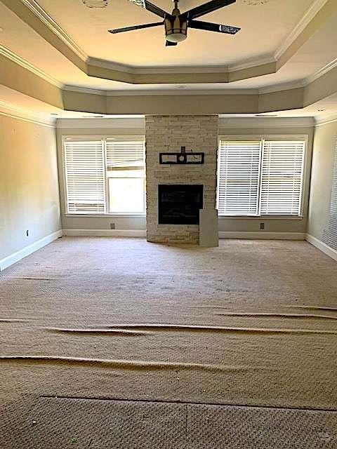 168 Harmony Grove Rd, Lilburn, GA 30047 - unfurnished living room featuring a tray ceiling, crown molding, ceiling fan, a fireplace, and baseboards