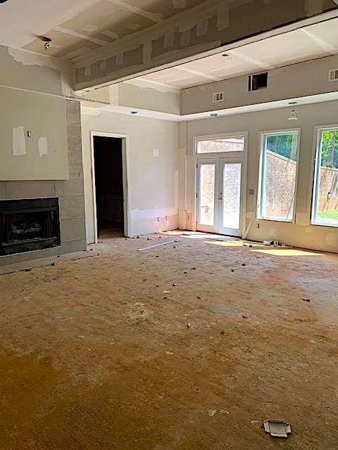 168 Harmony Grove Rd, Lilburn, GA 30047 - unfurnished living room featuring a tiled fireplace and french doors