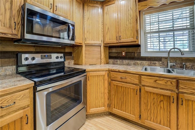 1240 H D Atha Rd, Monroe, GA 30655 - kitchen featuring light wood finished floors, stainless steel appliances, a sink, backsplash, and light countertops