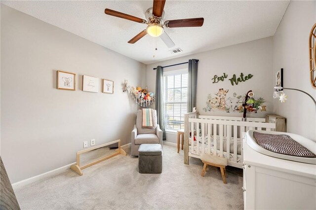 bedroom featuring carpet flooring, a nursery area, and ceiling fan