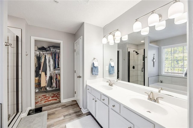 bathroom with shower with separate bathtub, vanity, hardwood / wood-style flooring, and a textured ceiling