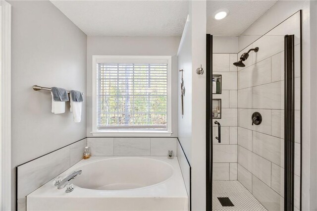 bathroom with a healthy amount of sunlight, a textured ceiling, and plus walk in shower