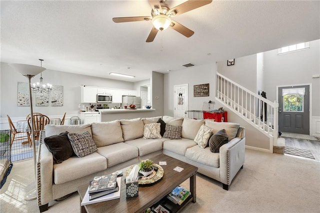 living room with light carpet and ceiling fan with notable chandelier