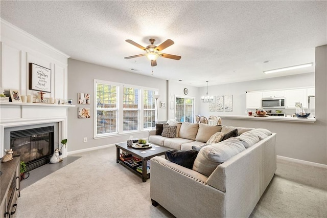 living room with a textured ceiling, ceiling fan with notable chandelier, and light carpet