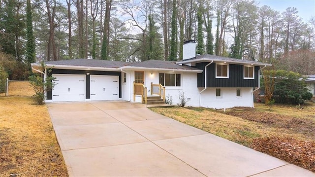 split level home with driveway, a chimney, and an attached garage