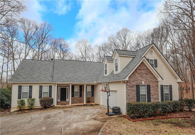 cape cod home with a garage, stone siding, and driveway