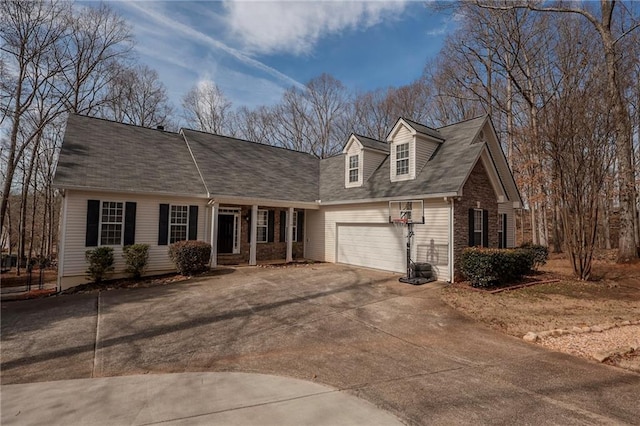 cape cod home featuring a garage, driveway, and brick siding