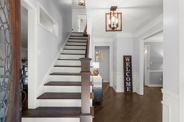 foyer entrance featuring dark hardwood / wood-style flooring, crown molding, and an inviting chandelier