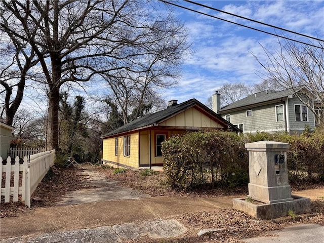 view of front facade featuring board and batten siding, fence, and a chimney