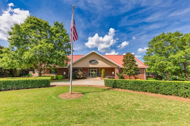 ranch-style home featuring brick siding, metal roof, and a front lawn