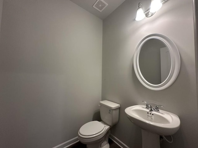 bathroom with toilet, baseboards, visible vents, and a sink