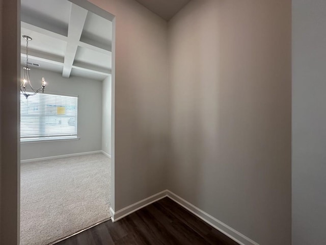 interior space with baseboards, dark wood finished floors, coffered ceiling, beamed ceiling, and an inviting chandelier