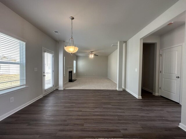 unfurnished living room with visible vents, a fireplace with flush hearth, a ceiling fan, carpet flooring, and baseboards