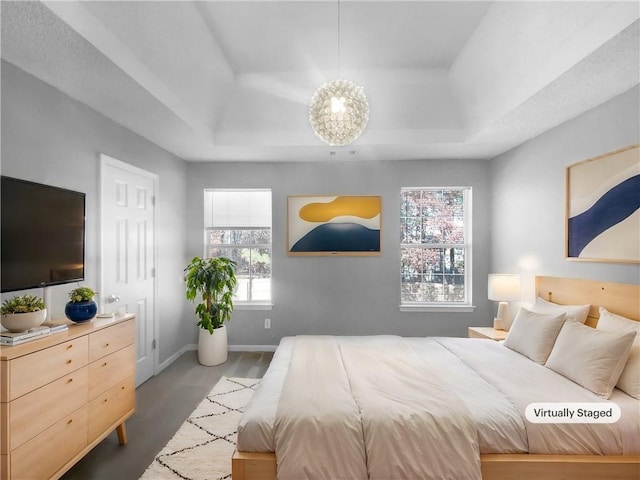 bedroom featuring wood-type flooring, a tray ceiling, and multiple windows