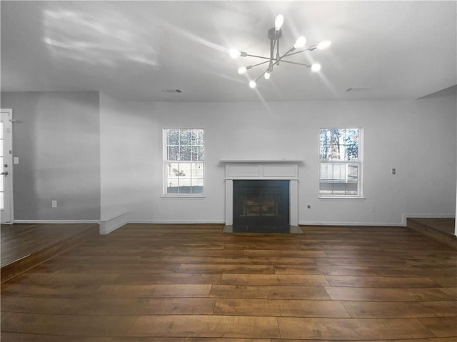 unfurnished living room featuring a chandelier and dark wood-type flooring